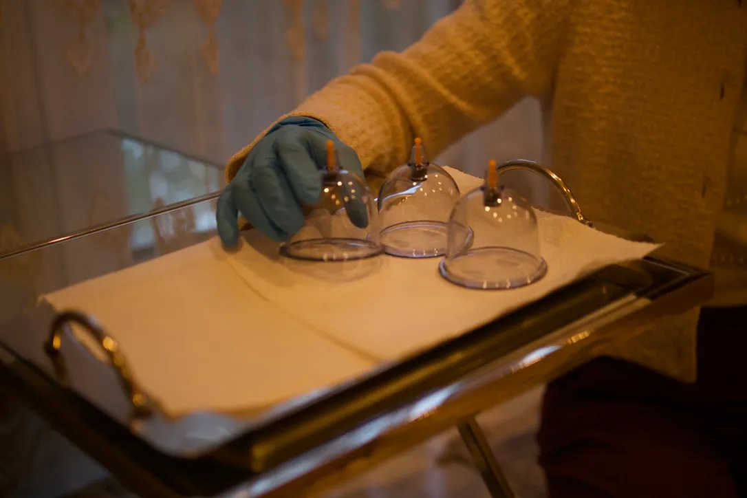 Three cupping cups set out on a clean tray by a gloved hand.